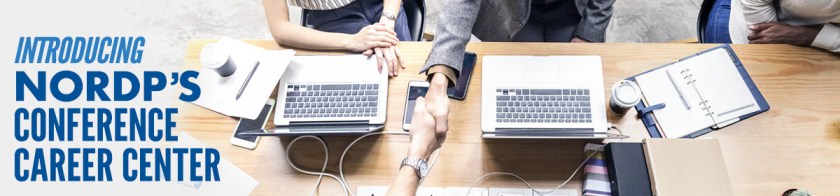 Handshake across a table with computers